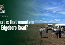 What Is That Mountain on Edgeboro Road? A group of about a dozen visitors stands on bare graded ground at the Edgeboro Road landfill beside two white shuttle buses, under a blue sky with scattered clouds. Overlaid title card reads: Eyes on EB, Part 1 of 4, What is that mountain on Edgeboro Road?