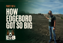 How Edgeboro Got So Big A man in sunglasses and an Eyes on EB t-shirt stands on the bare graded surface of the Edgeboro Road landfill under a blue sky, gesturing back over his shoulder toward the working face, with heavy equipment and a landfill ridge behind him. Overlaid title card reads: Eyes on EB, Part 2 of 4, How Edgeboro Got So Big.