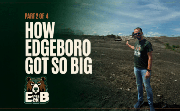 How Edgeboro Got So Big A man in sunglasses and an Eyes on EB t-shirt stands on the bare graded surface of the Edgeboro Road landfill under a blue sky, gesturing back over his shoulder toward the working face, with heavy equipment and a landfill ridge behind him. Overlaid title card reads: Eyes on EB, Part 2 of 4, How Edgeboro Got So Big.