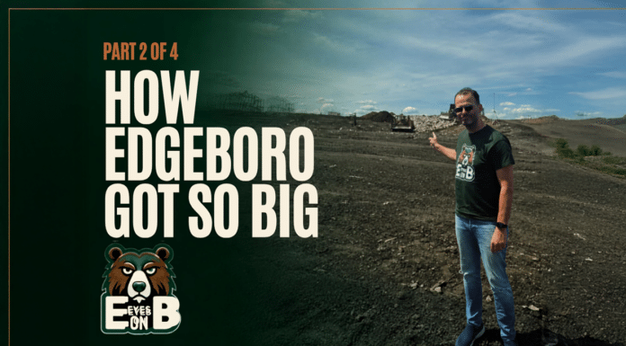 How Edgeboro Got So Big A man in sunglasses and an Eyes on EB t-shirt stands on the bare graded surface of the Edgeboro Road landfill under a blue sky, gesturing back over his shoulder toward the working face, with heavy equipment and a landfill ridge behind him. Overlaid title card reads: Eyes on EB, Part 2 of 4, How Edgeboro Got So Big.